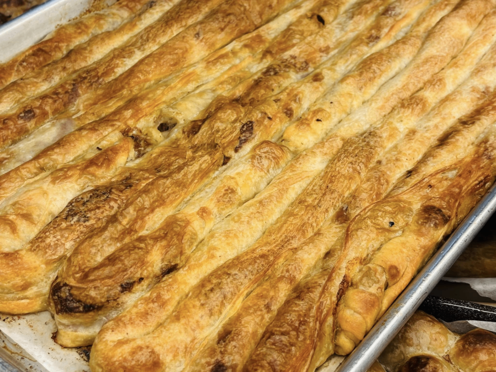 Tray of long, coiled beef burek with golden flaky layers fresh from the oven