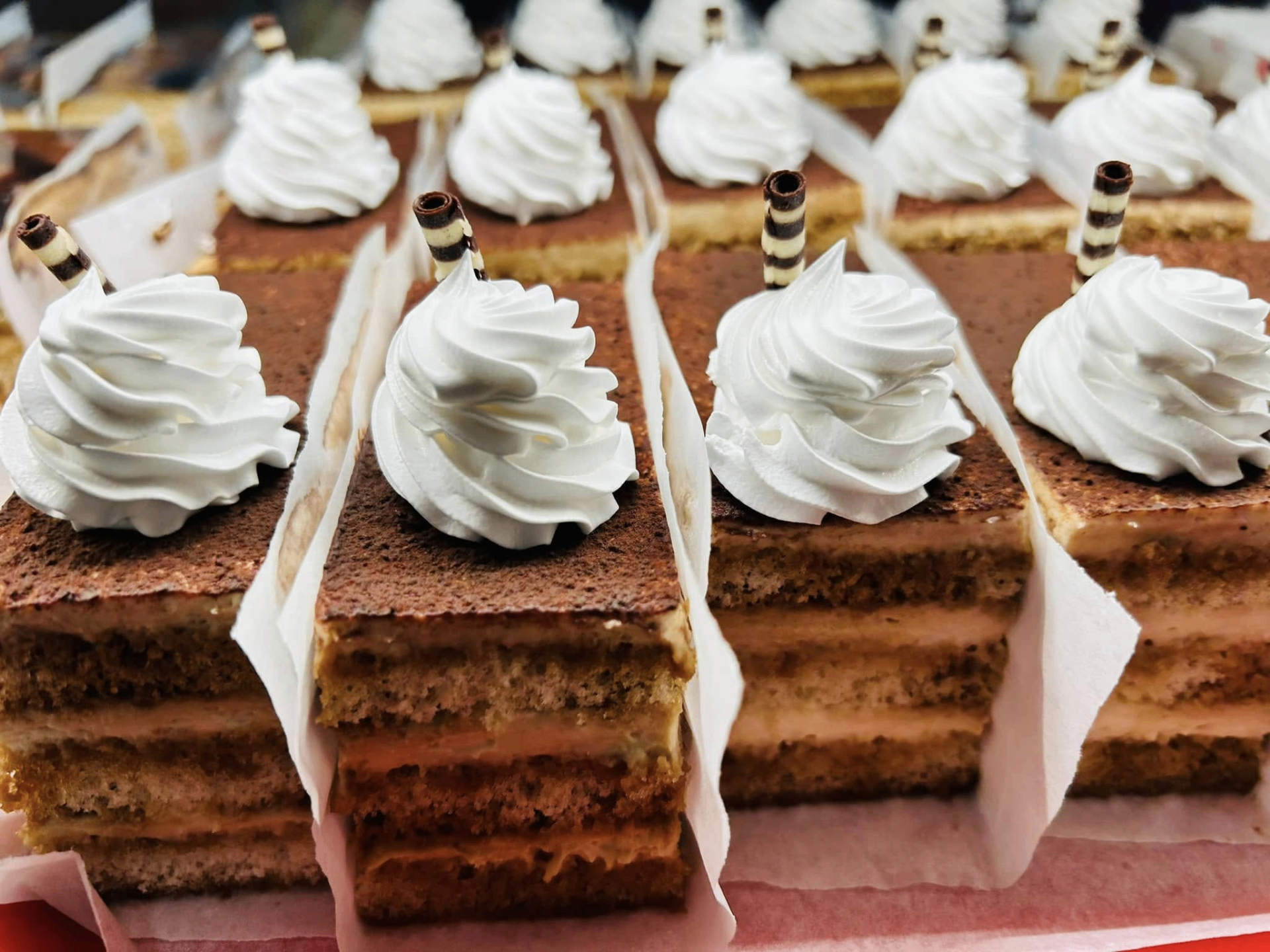 Layered honey cake slices topped with cream rosettes and wafer rolls