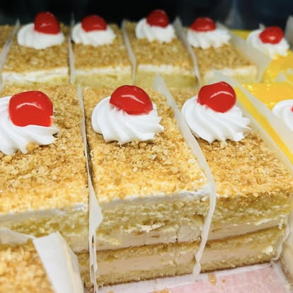 Vanilla crumb cake squares topped with cream rosettes and cherries