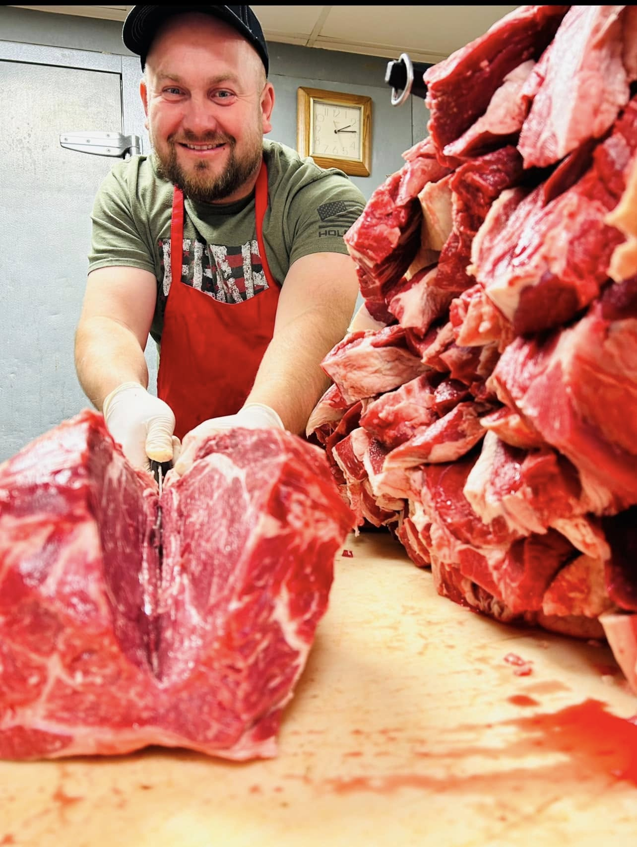 Alen smiling behind the butcher block, hand-cutting fresh halal beef